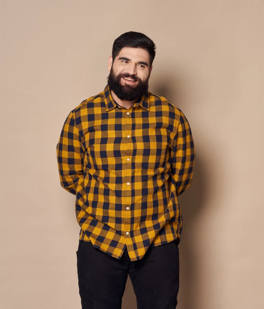 Product Cat - Weight Loss - Daytryp RX Portrait of a smiling man with a beard wearing a yellow and navy blue plaid shirt.