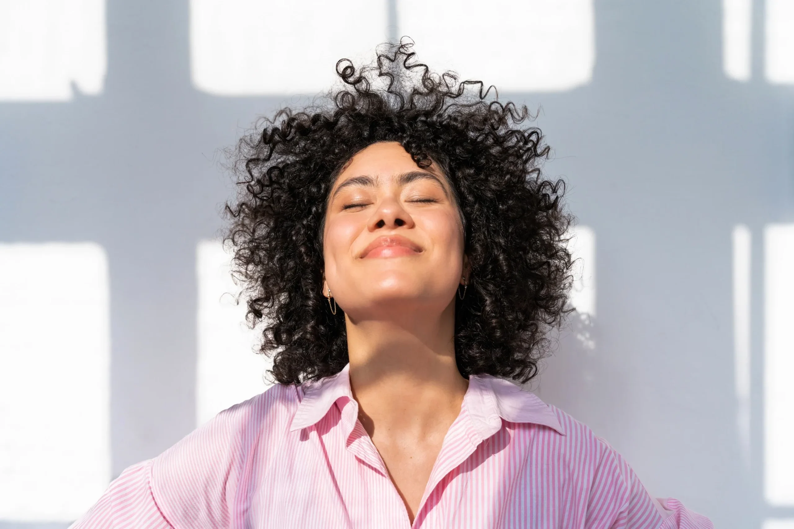 Woman enjoying sunlight with eyes closed and a peaceful smile.