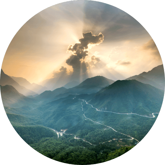 1 - Daytryp RX A circular image of mountains and valleys with a winding road and sun rays breaking through the clouds.