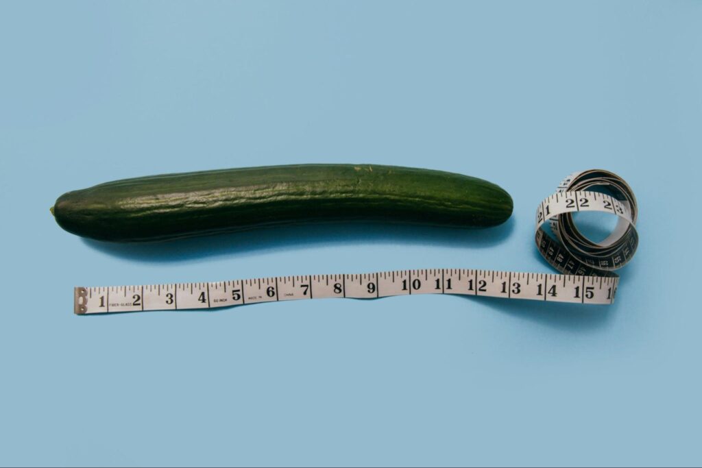 Cucumber with measuring tape symbolizing size measurement on a blue background