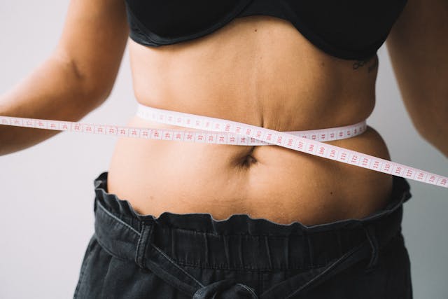  woman measuring waist with tape showing before and after results linked to mic B12 injections and improved metabolism