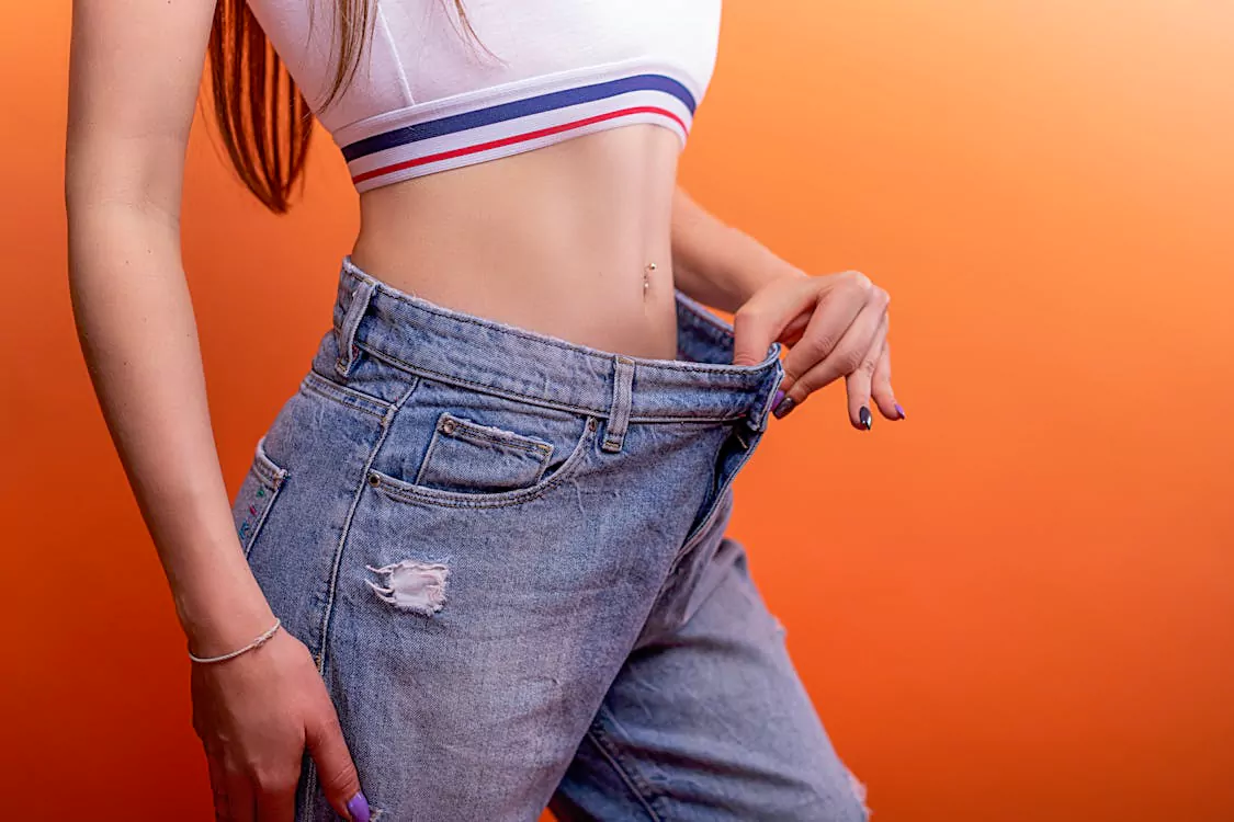 woman wearing loose jeans showing fat loss results from mic B12 injections