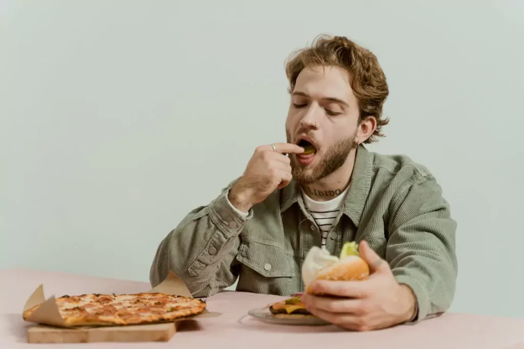 A person eating a burger and a pizza
