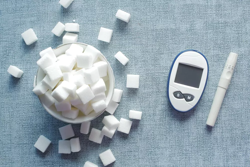 Glucometer and insulin pen beside sugar cubes representing blood sugar control and semaglutide use for diabetes management