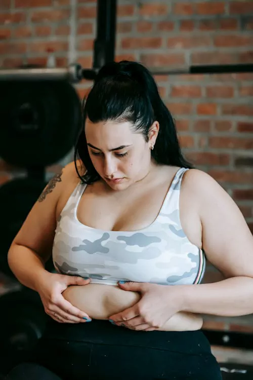  Woman holding abdominal fat highlighting weight loss challenges treated with tirzepatide