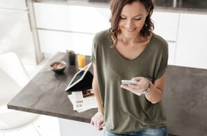 A woman at home reviewing wellness options on her smartphone