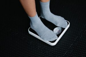 Person standing on a scale tracking weight while exploring semaglutide, tirzepatide, and retatrutide options