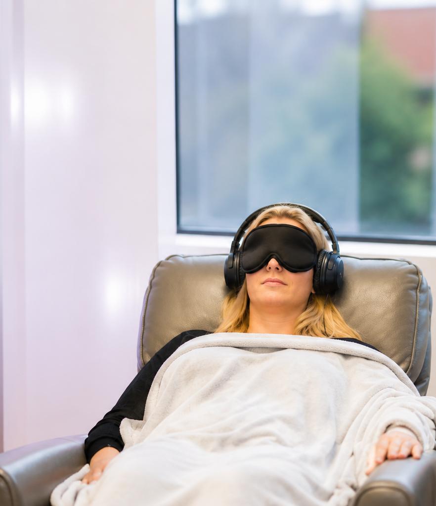 A person lying in bed with sleep mask and headphones