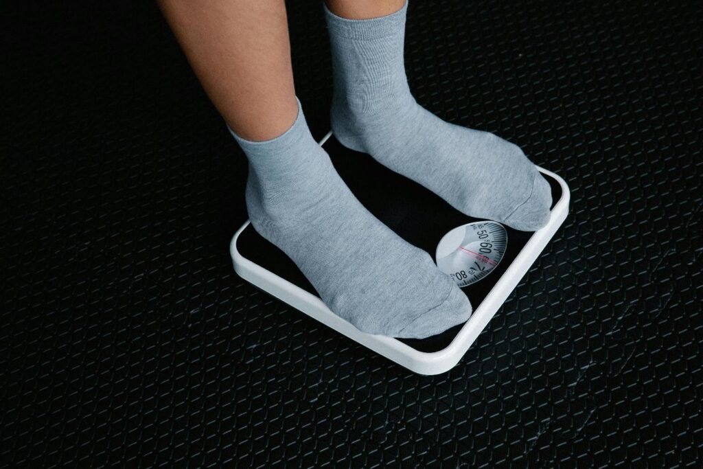 A person using the weighing machine to measure their weight 