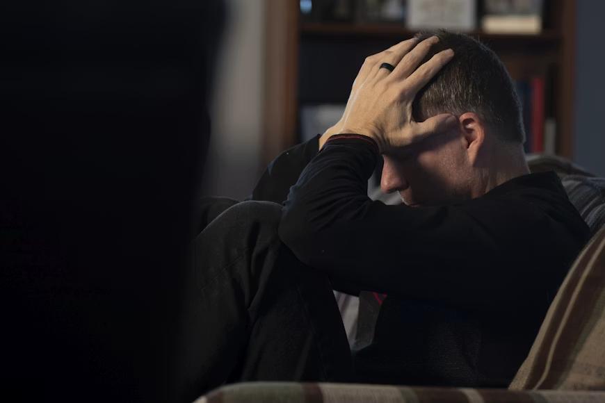 An image of a man holding his head in his hands