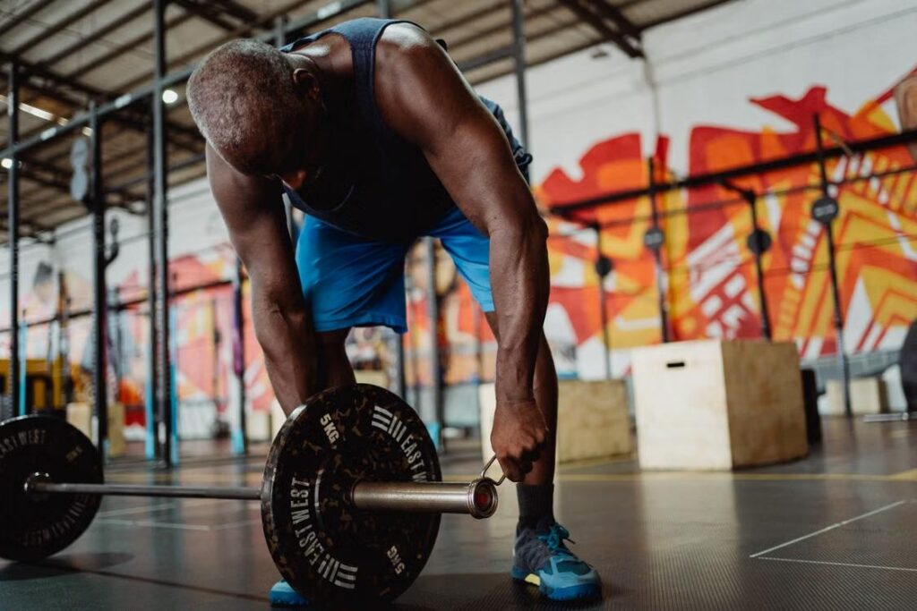 man lifting a barbell in a gym while experiencing symptoms associated with low testosterone and reduced physical performance
