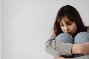 woman sitting alone while experiencing emotional distress and barriers to accessing mental health treatment
