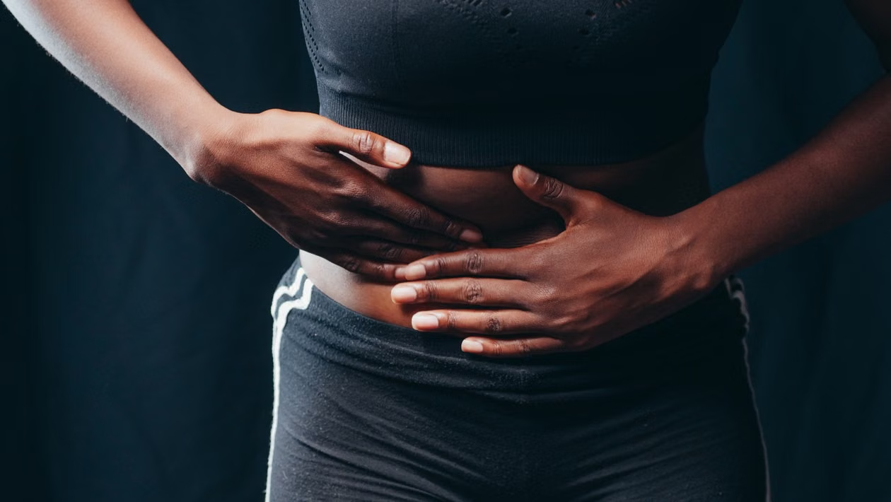 woman holding her abdomen representing liver health, metabolic stress, and the need for glutathione support