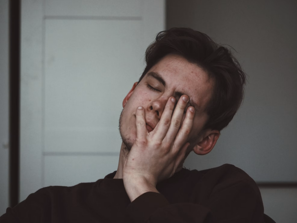 man sitting alone with his hands covering his face while experiencing emotional distress associated with PTSD
