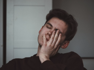 man sitting alone with his hands covering his face while experiencing emotional distress associated with PTSD