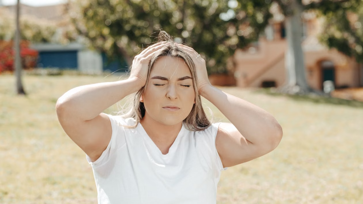 woman holding her head while experiencing fatigue and brain fog associated with long COVID symptoms