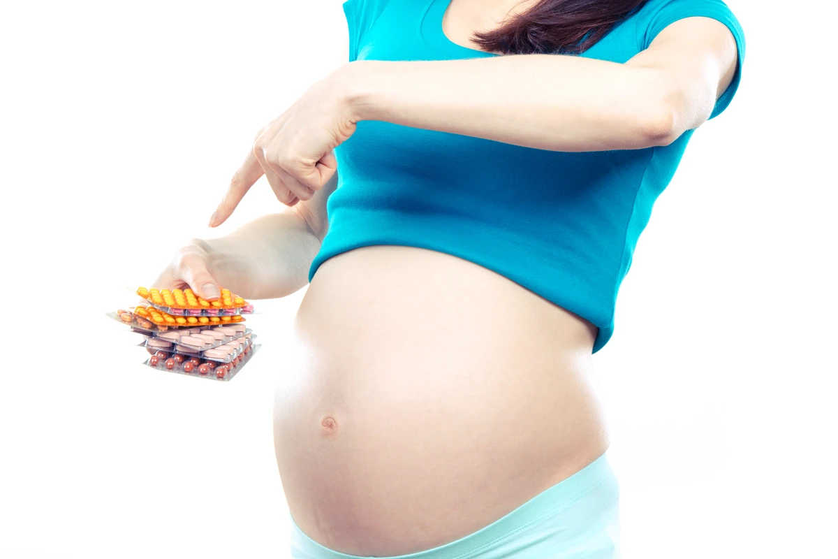 A pregnant woman holding medication pills, highlighting concerns about using weight loss medications during pregnancy