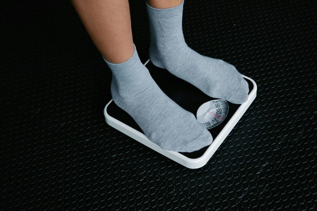 A person using the weighing machine to measure their weight 