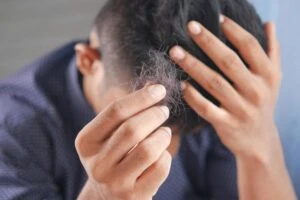 person holding shed hair while examining thinning hair and early hair loss symptoms
