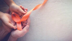 Hands holding an orange ribbon symbolizing multiple sclerosis awareness.