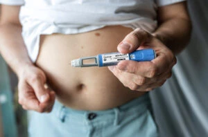 Person preparing for a subcutaneous self-injection into the abdomen with a Daytryp injection pen.