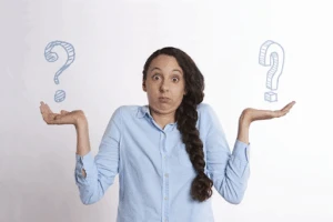 A woman with a confused expression shrugs with her palms up, with sketched question marks floating above her hands.