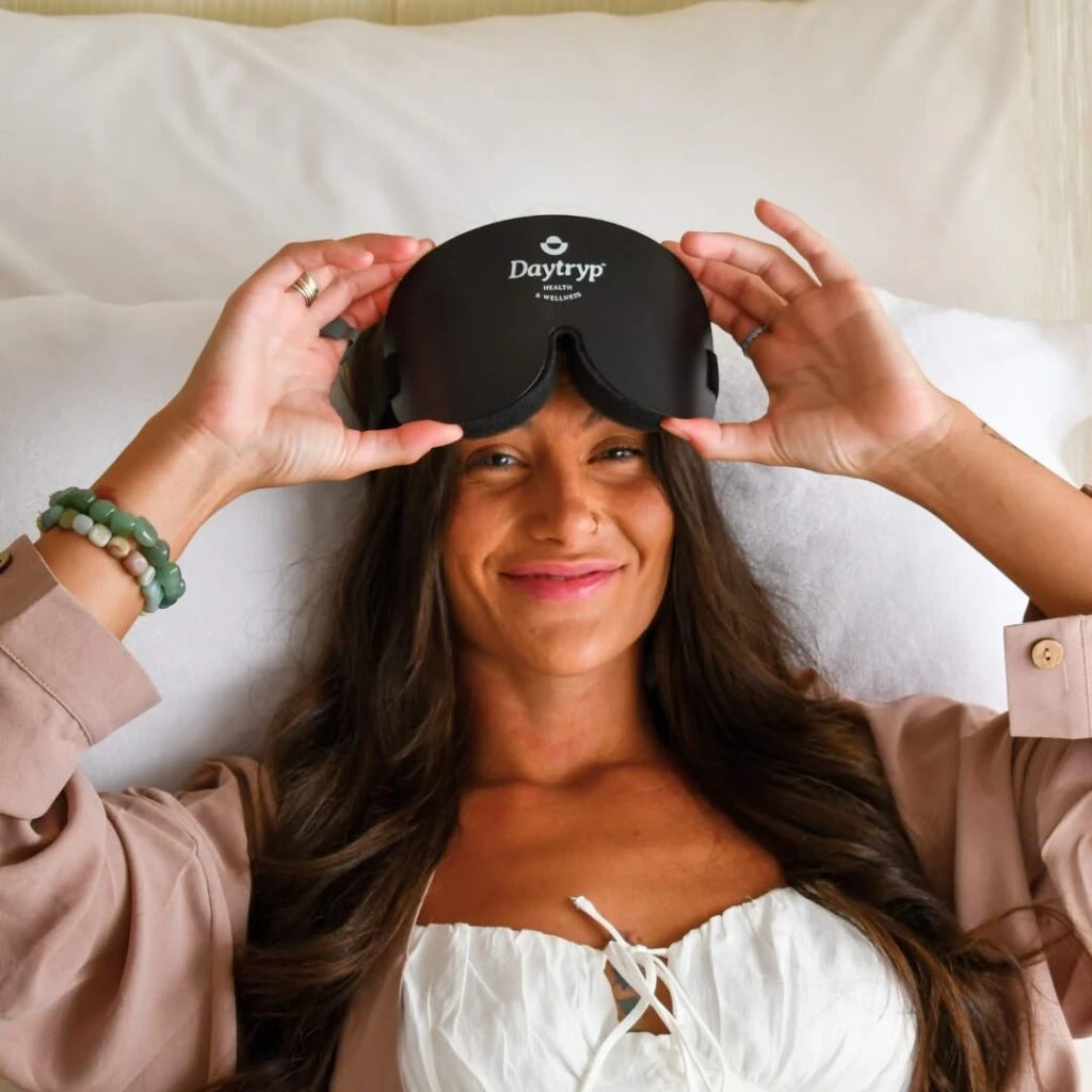 10 Essential Tips for Safe Therapy Sessions - Daytryp RX A person lying on pillows lifts a black sleep mask labeled "Daytryp" and smiles.