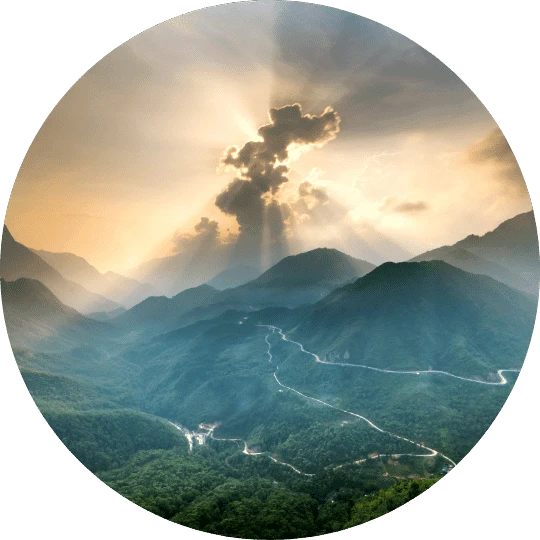 1 - Daytryp RX A circular image of mountains and valleys with a winding road and sun rays breaking through the clouds.