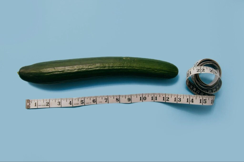 Cucumber with measuring tape symbolizing size measurement on a blue background